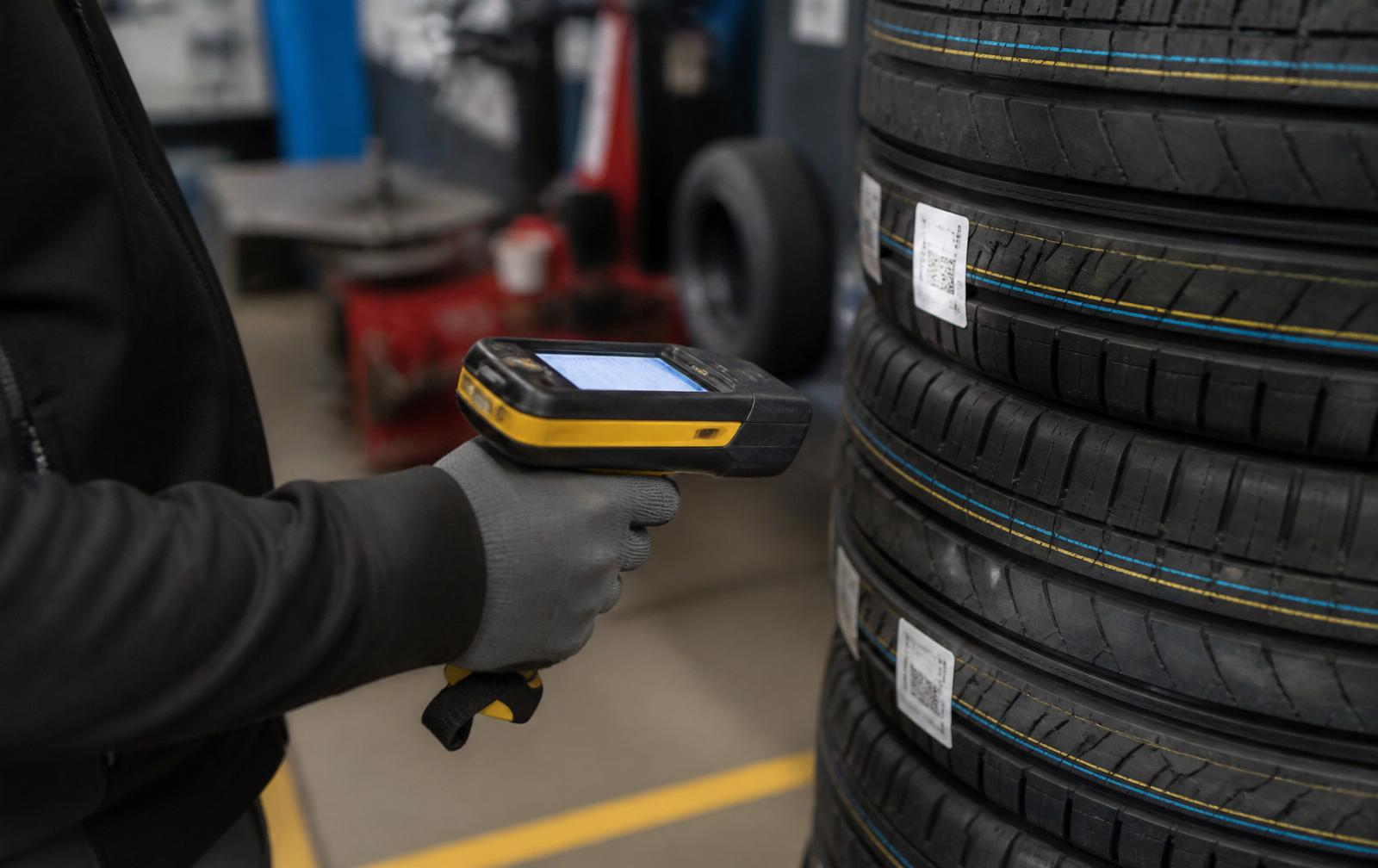 Technician using a handheld UHF RFID reader on a tyre in a fitting bay